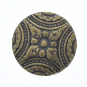 May include: A round, brass button with a decorative, floral design. The button has a raised, textured surface with a central flower surrounded by four smaller flowers.