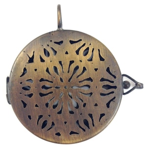以下が含まれることがあります： 装飾的なカットアウトデザインが施された丸い真鍮製のペンダント。ペンダントの上部に吊り下げ用のループがあります。