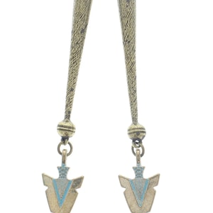 Puede incluir: Un par de pendientes colgantes con un acabado texturizado de color bronce. Cada pendiente presenta una parte superior larga y delgada, una pequeña bola y un colgante en forma de punta de flecha con detalles azules.