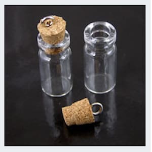 Peut inclure: Trois petites bouteilles en verre avec des bouchons en liège et des anneaux métalliques. Les bouteilles sont transparentes et de forme ronde. Les bouchons sont bruns et ont une surface texturée.