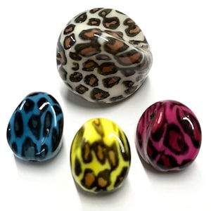 May include: Four round, glossy beads with a leopard print design. The beads are in different colors: white, blue, yellow, and pink.