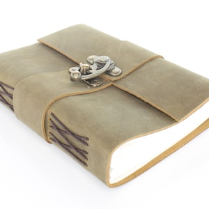 May include: A brown leather journal with a metal clasp and a decorative stitching detail. The journal is closed and lying on a white surface.