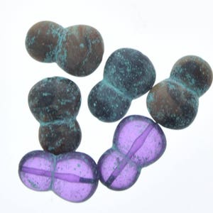 May include: Five glass beads, two are purple and three are a mottled blue-green color. The beads are shaped like a figure eight.