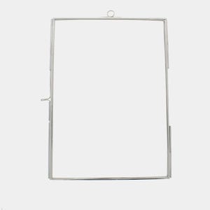 May include: A silver metal picture frame with a hanging loop at the top.
