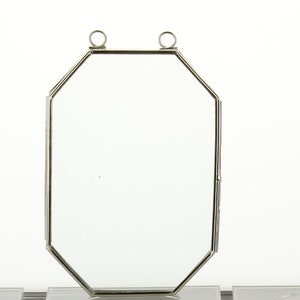 May include: A silver octagonal picture frame with two hanging loops at the top.