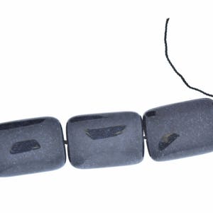 May include: A strand of dark gray rectangular beads strung on black thread.