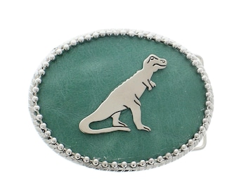May include: A silver belt buckle with a green leather background and a silver dinosaur silhouette.