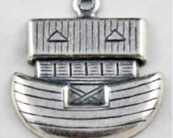 May include: A silver charm in the shape of Noah's Ark. The ark has a pointed roof with two small triangles on either side. The ark has a detailed design with lines and a cross on the front.