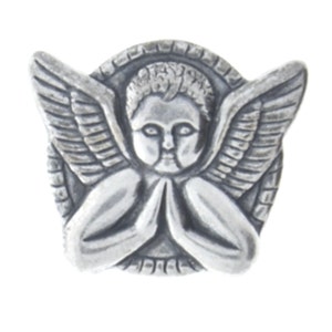 Puede incluir: Un pin de ángel plateado detallado, con alas extendidas y manos juntas. La cara del ángel está centrada, con un borde en forma de halo alrededor de la cabeza. El pin probablemente está hecho de metal.