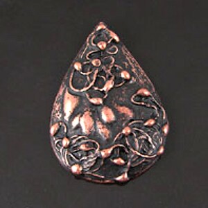 May include: A teardrop-shaped pendant with a copper finish, featuring a raised design of stylized flowers and leaves.