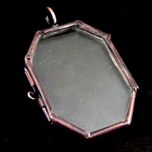 May include: Octagonal shaped locket with a copper coloured frame and a clear glass insert. The locket has a small loop at the top for hanging.