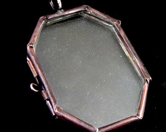 May include: Octagonal shaped locket with a copper coloured frame and a clear glass insert. The locket has a small loop at the top for hanging.
