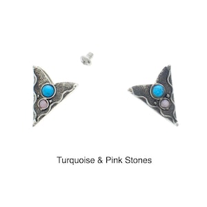 Puede incluir: Un par de pendientes triangulares plateados con piedras turquesa y rosas. Los pendientes se sujetan con un cierre de rosca.