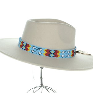 May include: A light beige fedora hat with a blue beaded band featuring a geometric pattern in red, yellow, and white.