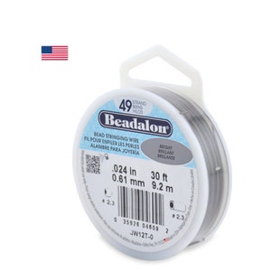 Pode incluir: Um carretel de fio para enfiar contas Beadalon de 49 fios. O fio tem 0,61 mm de espessura e vem em um rolo de 9,2 metros. O carretel é branco com texto preto e um código de barras.