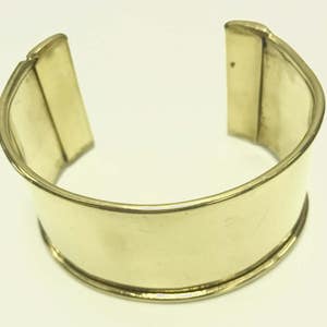 May include: A gold-toned metal bangle bracelet with a simple, polished design.
