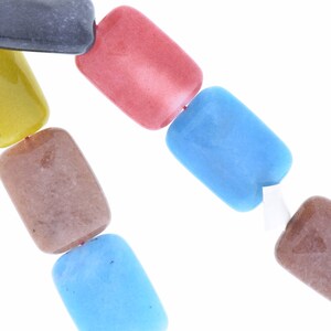 May include: A strand of colorful rectangular beads, including yellow, brown, blue, red, and gray, strung on a red cord.