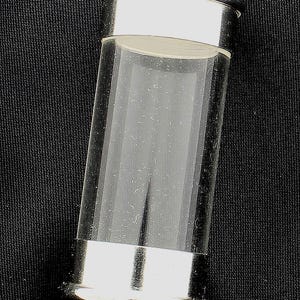 May include: A clear glass vial with silver-colored metal bands at the top and bottom, and a matching cap with a small loop. The vial is cylindrical and appears empty. The background is black.