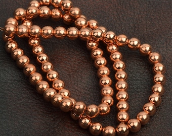 May include: A strand of copper-colored beads, arranged in a circular shape, on a brown leather background.