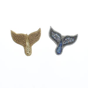 May include: Two embroidered whale tail patches, one gold and one silver with blue iridescent sequins.