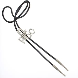May include: A black bolo tie with a rhinestone "Love 8" design. The tie has a black cord and silver-toned metal tips. The decorative element is made of clear rhinestones.