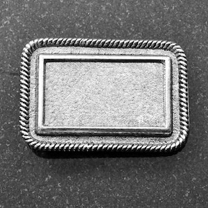 May include: A silver-colored metal rectangular plaque with a rope-like border. The plaque has a blank space in the center.