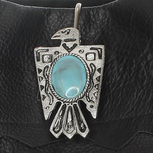May include: A silver eagle pendant with a turquoise stone, attached to a black leather strap.