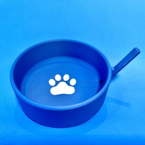 May include: Blue silicone pet bowl with a white paw print design and a spout for easy water access.