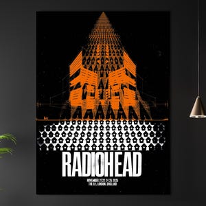 Puede incluir: Un póster enmarcado con un diseño de concierto de Radiohead. La obra de arte tiene una combinación de colores naranja y negro, con un diseño geométrico de edificio. El nombre de la banda está en letras blancas. El póster también incluye la fecha y el lugar del concierto.