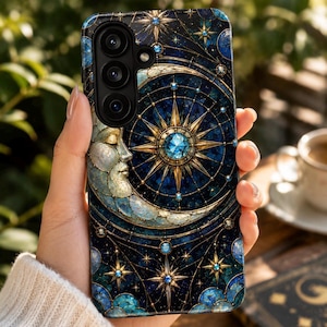 Könnte beinhalten: Eine Smartphone-Hülle mit einem dunkelblauen Himmelsdesign, das ein goldenes Mondsichelgesicht, einen zentralen Stern mit blauem Edelsteinakzent und verstreute kleine Sterne zeigt. Das komplexe Muster ähnelt Buntglas mit goldenen Linien.