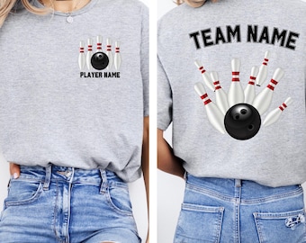 Op de afbeelding: Lichtgrijs t-shirt met een bowlingontwerp. De voorkant toont een bowlingbal en kegels met de tekst "PLAYER NAME". De achterkant heeft een vergelijkbaar ontwerp met de tekst "TEAM NAME". Het shirt is gemaakt van zacht materiaal.