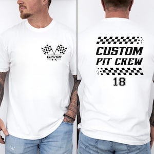 以下が含まれることがあります： 白のTシャツ。前面には、黒と白のチェッカーフラッグのデザインと「CUSTOM」の文字。背面には「CUSTOM PIT CREW」と数字の「18」が黒色でプリントされています。