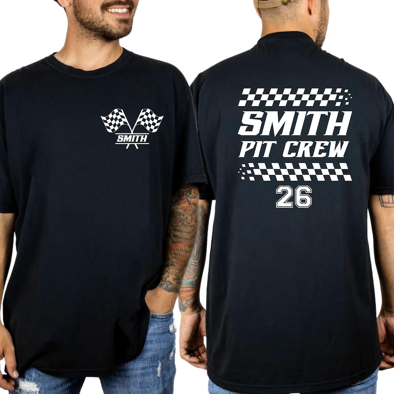 以下が含まれることがあります： 白のグラフィックが施された黒いTシャツ。前面には2つのチェッカーフラッグと「SMITH」の文字が描かれています。背面には「SMITH PIT CREW」と数字の「26」がチェッカーフラッグのアクセントとともに表示されています。カジュアルなクルーネックTシャツ。