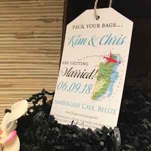 May include: A white luggage tag with a map of Belize and the text "Pack your bags... Kim & Chris are getting married! 06.09.18 Ambergris Caye, Belize Don't forget your passports!"