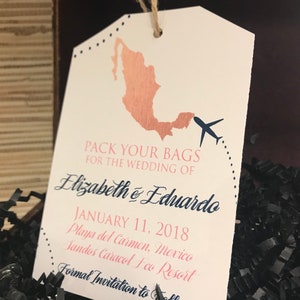May include: A white luggage tag with a brown outline and a pink and blue design. It says "Pack your bags for the wedding of Elizabeth & Eduardo January 11, 2018 Playa del Carmen, Mexico Sandos Caracol Eco Resort Formal Invitation to Follow"