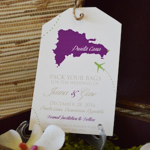May include: A white luggage tag with a purple outline of the Dominican Republic and the text "Punta Cana". The tag also includes the text "Pack your bags for the wedding of Jeana & Geno, December 28, 2016, Punta Cana, Dominican Republic. Formal Invitation to Follow, THEKNOT.COM/US/KARARO-RYAN, KNOT PIN: 2016."