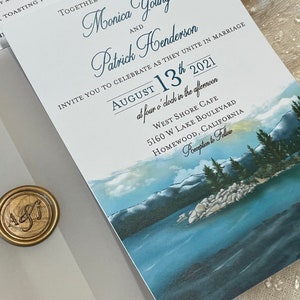 May include: A wedding invitation with a blue and white watercolor background featuring a mountain range and a lake. The invitation is for Monica Young and Patrick Henderson, who are getting married on August 13th, 2021 at West Shore Cafe in Homewood, California.