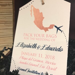 May include: A white luggage tag with a brown outline of Mexico, a blue airplane, and the text "Pack your bags for the wedding of Elizabeth & Eduardo January 11, 2018 Playa del Carmen, Mexico Sandos Caracol Eco Resort Formal Invitation to Follow"