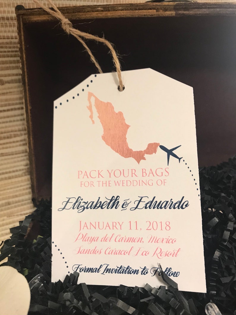 May include: A luggage tag with a rose gold outline of Mexico and a blue airplane. The tag says "Pack your bags for the wedding of Elizabeth & Eduardo, January 11, 2018, Playa del Carmen, Mexico, Sandos Caracol Eco Resort, Formal Invitation to Follow."
