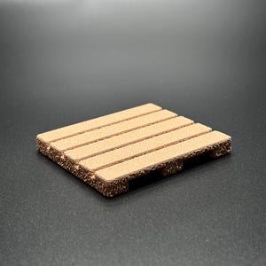 May include: A small, light brown miniature pallet made of wood. The pallet has four horizontal planks and three support blocks on each end. The wood has a textured surface and is designed to resemble a real shipping pallet.