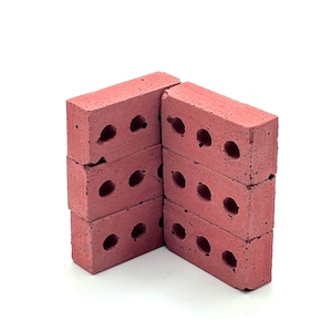 Puede incluir: Seis ladrillos rosas apilados en dos columnas, cada uno con tres agujeros circulares. Los ladrillos son de un color uniforme y parecen estar hechos de un material poroso. Los agujeros son claramente visibles. Fondo blanco.