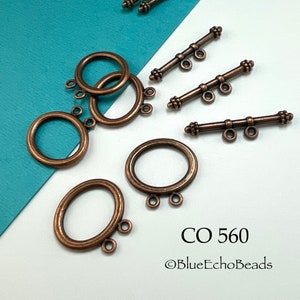 May include: A set of antique copper-toned metal clasps for jewelry making. The set includes three bar clasps and three round clasps, each with three loops. The clasps are arranged on a white surface with a blue background. The text "CO 560 @BlueEchoBeads" is visible in the lower right corner of the image.