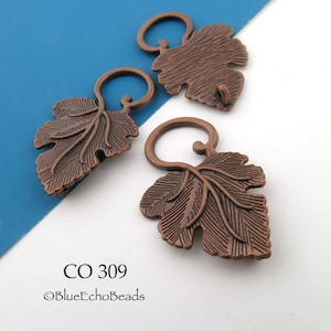 May include: Three copper-toned metal leaf-shaped pendants with a textured surface and a circular loop at the top. Each piece features a detailed vein pattern and a dark antique finish. The text CO 309 and BlueEchoBeads is printed below.