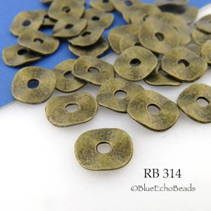 May include: A close-up of a pile of antique gold-toned metal spacer beads. The beads are flat and round with a hole in the center. The beads are arranged in a random pattern on a white surface. The text "RB 314 ©BlueEchoBeads" is visible in the bottom right corner of the image.
