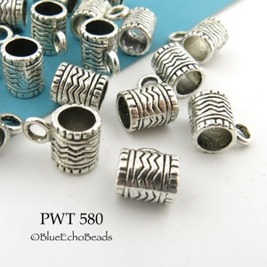 May include: A close-up of silver metal cord end caps with a textured design. The caps have a small loop at the top for attaching to a cord or chain. PWT 580 ©BlueEchoBeads