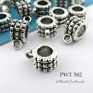 May include: Silver tone metal bead caps with a decorative design. The bead caps have a small loop at the top for attaching to jewelry.