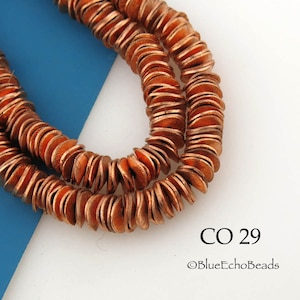 May include: Close-up of two strands of copper-colored, flat, round beads. The beads are stacked and have a slightly irregular shape. The background is white and blue. Text on the image reads "CO 29" and "©BlueEchoBeads".