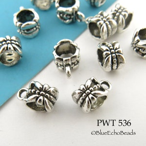 May include: Silver tone metal bead caps with a decorative butterfly design. The caps have a loop on the top for attaching to jewelry.