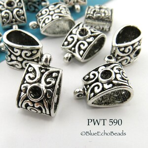 May include: Silver-toned metal pendant bails with an ornate design. The bails are shaped like a teardrop with a loop at the top.  The text "PWT 590 ©BlueEchoBeads" is visible in the image.