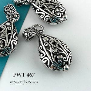 May include: Three silver filigree teardrop pendant charms with a swirl design. The charms have a shiny finish and are perfect for jewelry making.